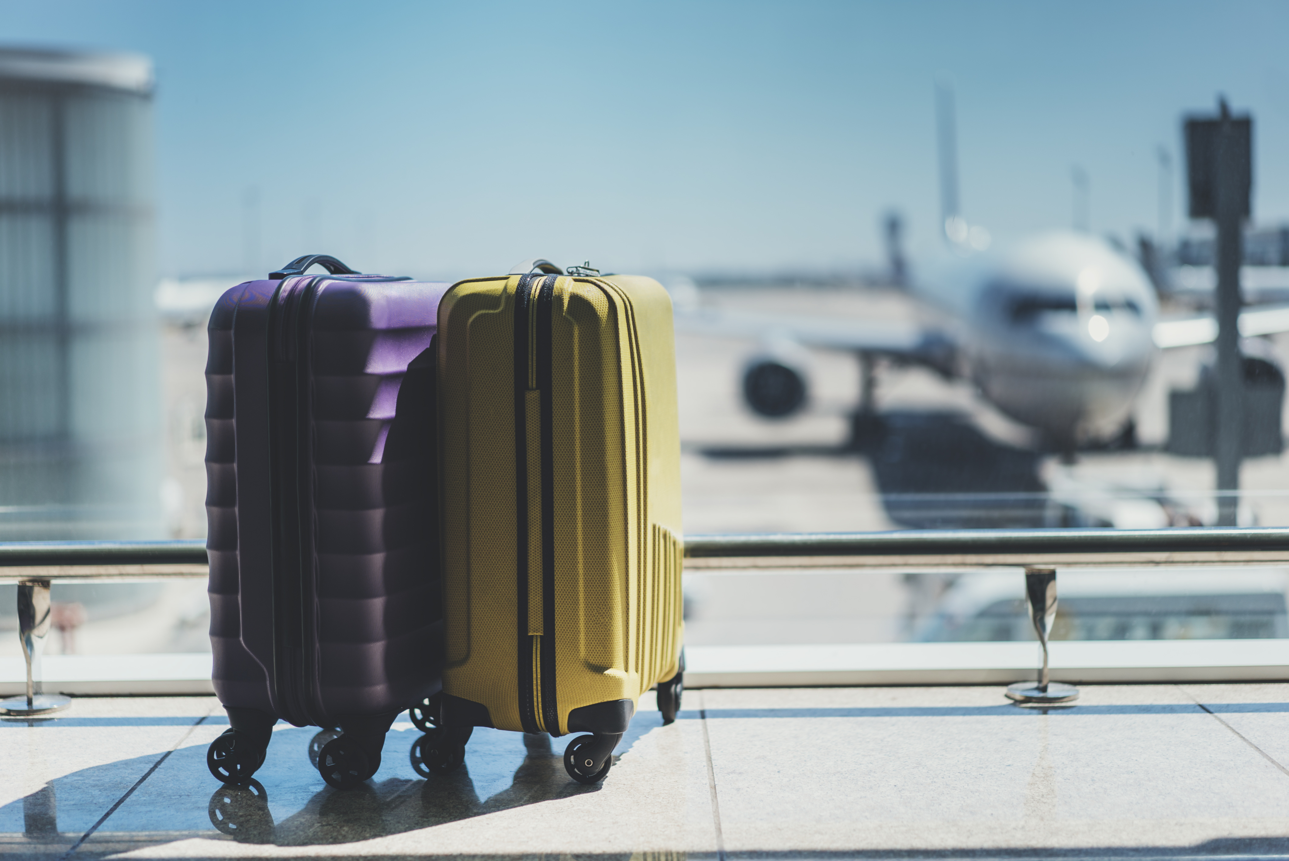 Two suitcases in the airport departure lounge, airplane in the blurred ...